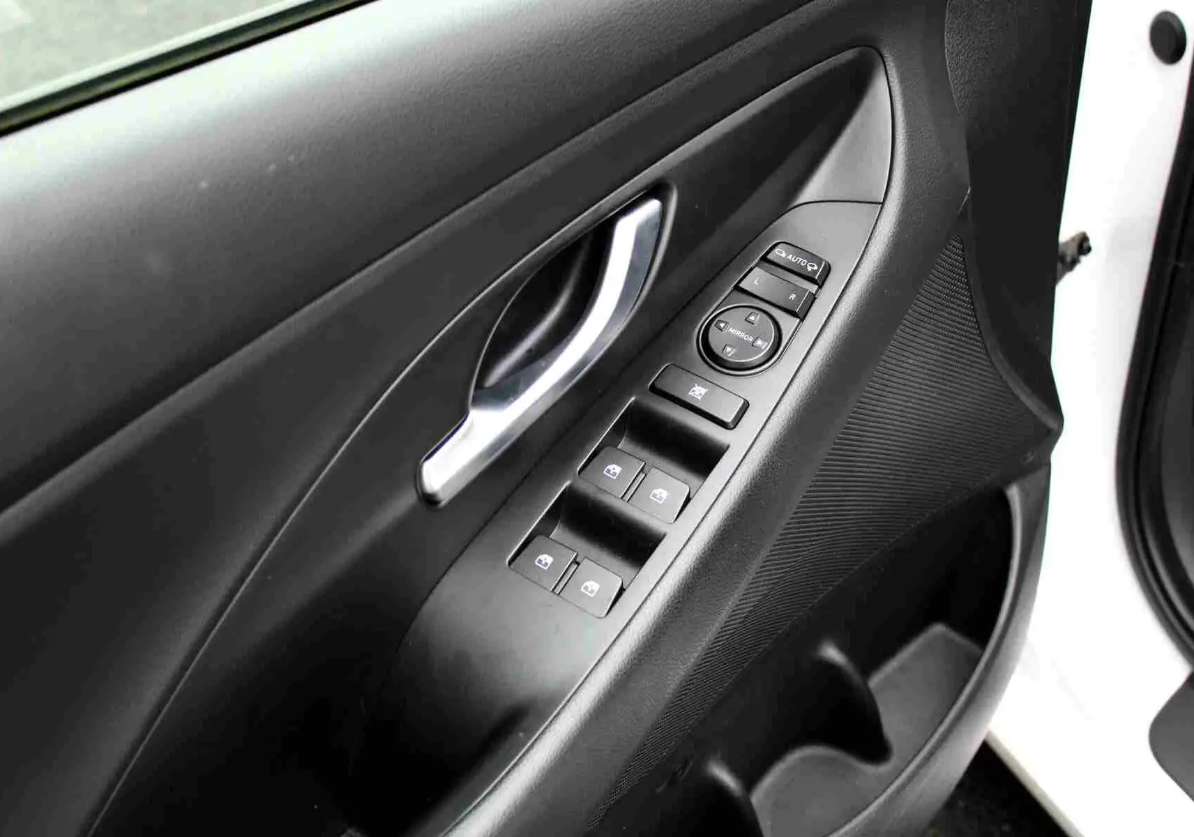 Gros plan sur la porte avant gauche d'une Hyundai i30 SW blanche avec commandes électriques des vitres et rétroviseurs.