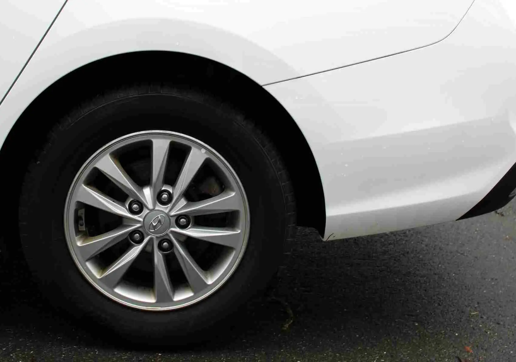 Gros plan sur la roue arrière gauche d'une Hyundai i30 SW blanche polaire avec jante alliage argentée.