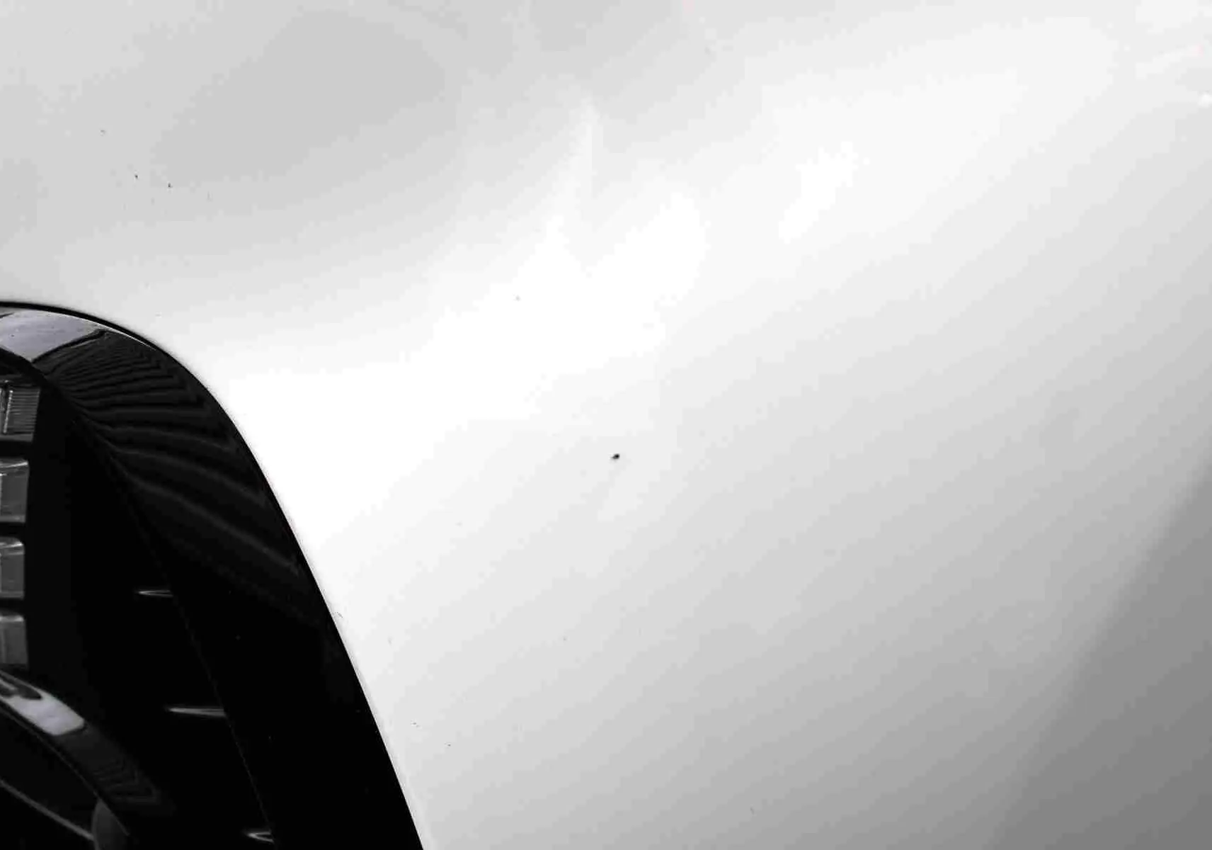 Vue rapprochée du capot blanc polaire d'une Hyundai i30 SW 2022 avec reflet flou d'une silhouette.