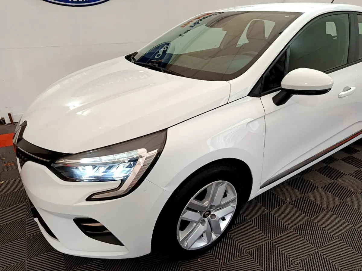 Renault Clio Business TCe 100 blanc vue 3/4 avant droit avec phares LED allumés et jantes alliage.