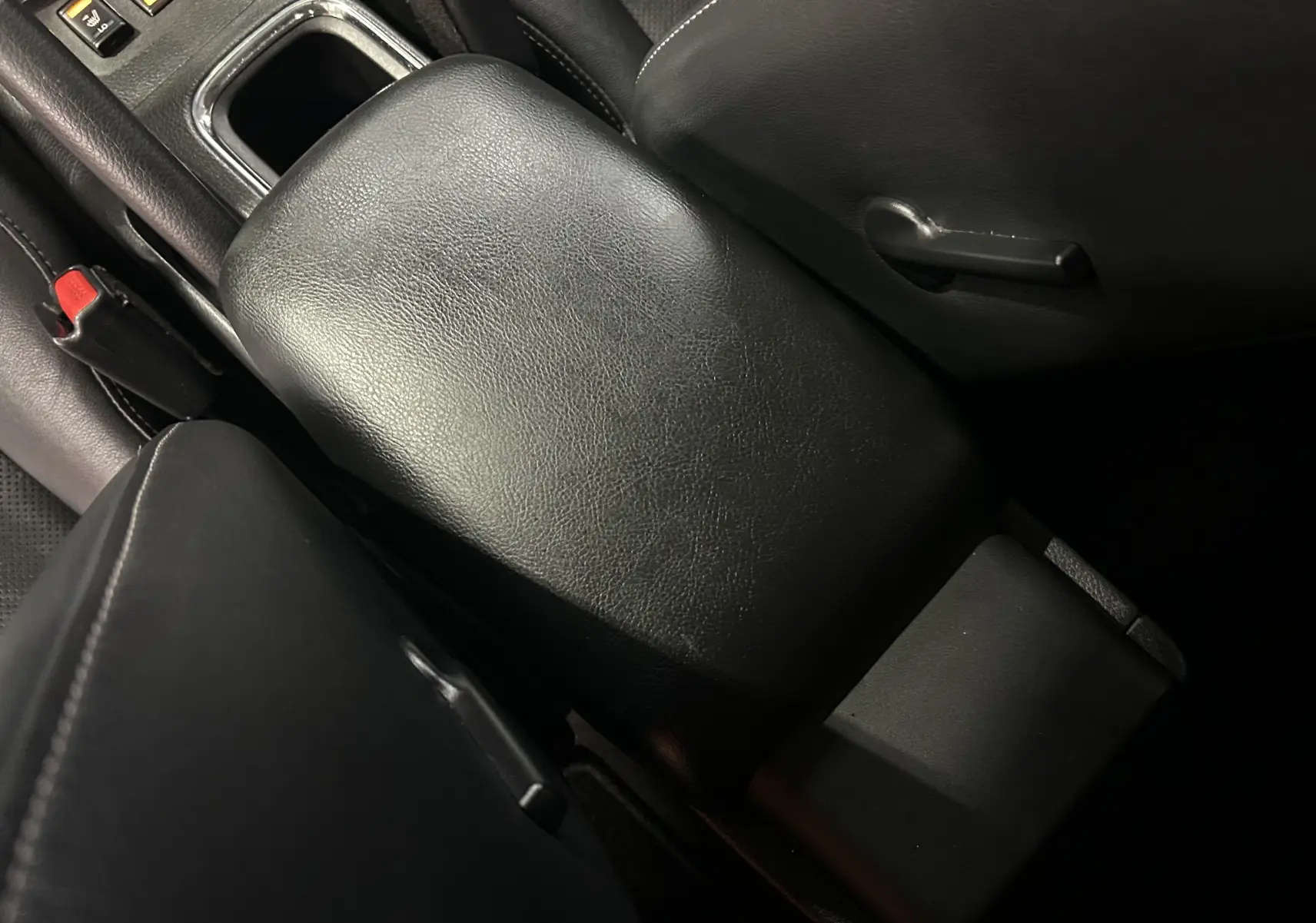 Gros plan sur l'accoudoir central en cuir noir de la Nissan Pulsar 1.5 dCi 110ch Ultimate, intérieur sombre.