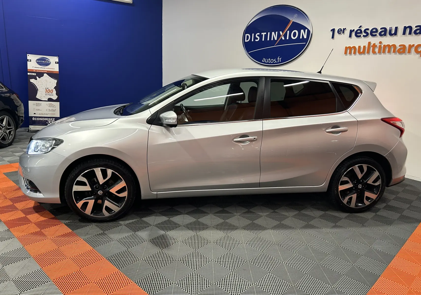 Vue latérale droite d'une Nissan Pulsar gris métallisé 5 portes, avec jantes alliage et intérieur cuir visible.