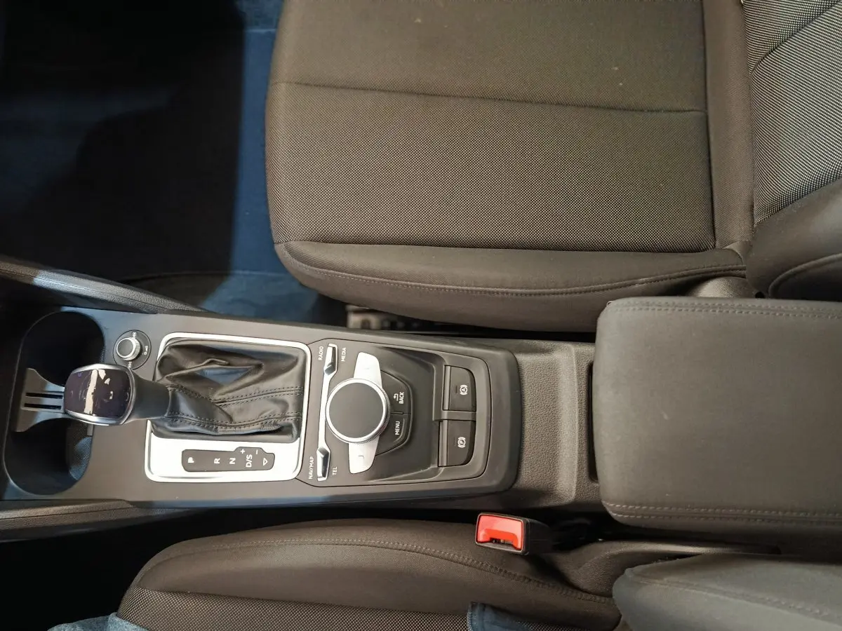 Vue plongeante sur la console centrale noire de l'Audi Q2 35 TFSI 150 S Tronic Business Line avec levier de vitesse automatique.