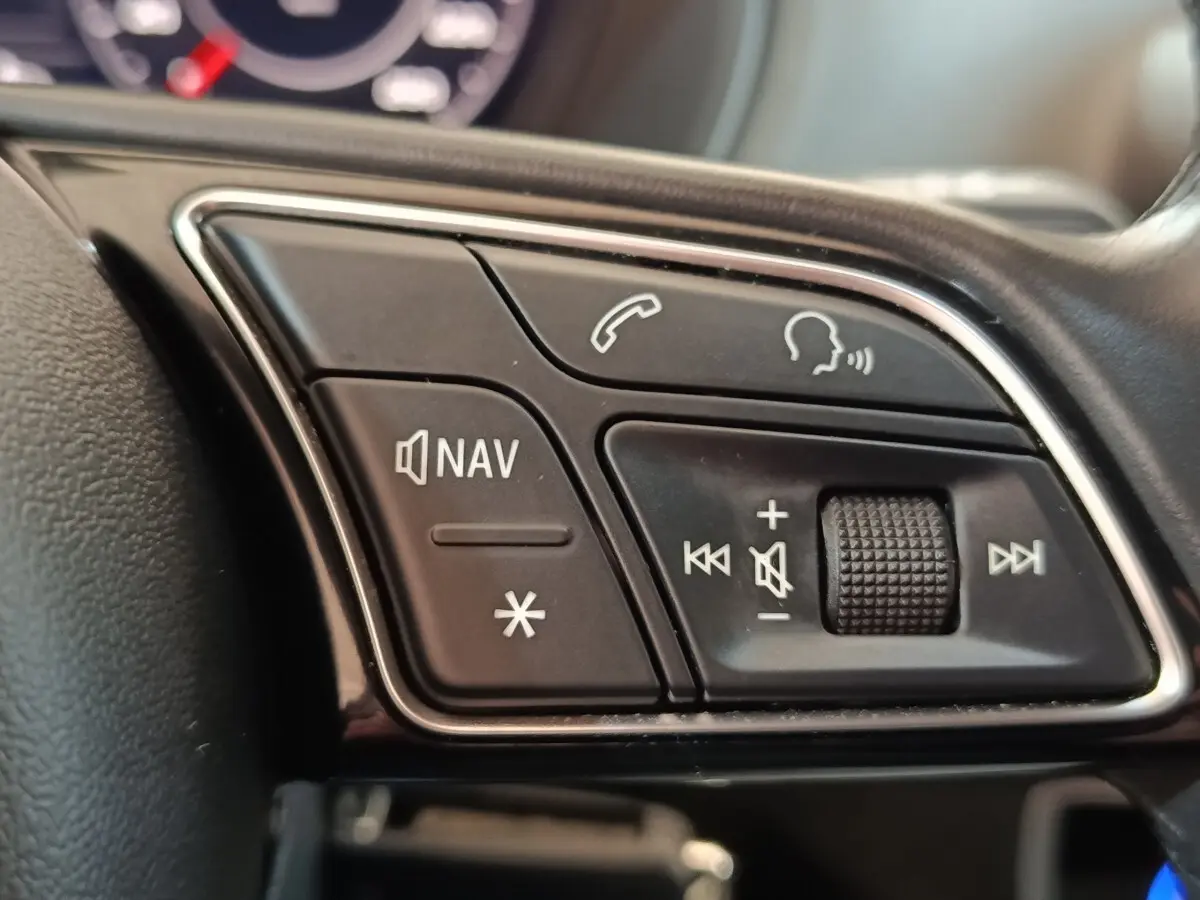 Gros plan sur les commandes audio et navigation au volant cuir noir de l'Audi Q2 35 TFSI 2022.