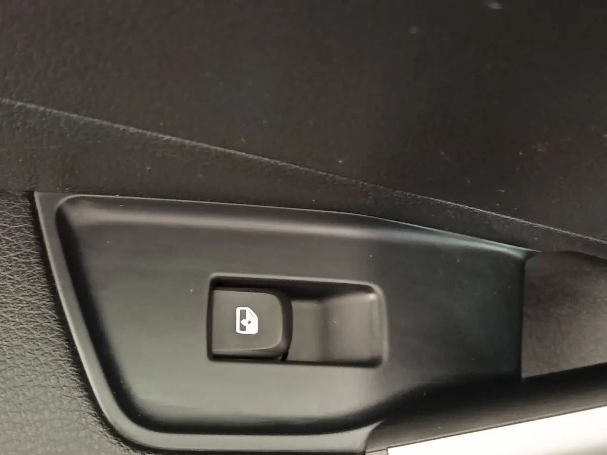 Bouton de commande de lève-vitre électrique sur panneau de porte intérieur noir, détail d'Audi Q2 2022.