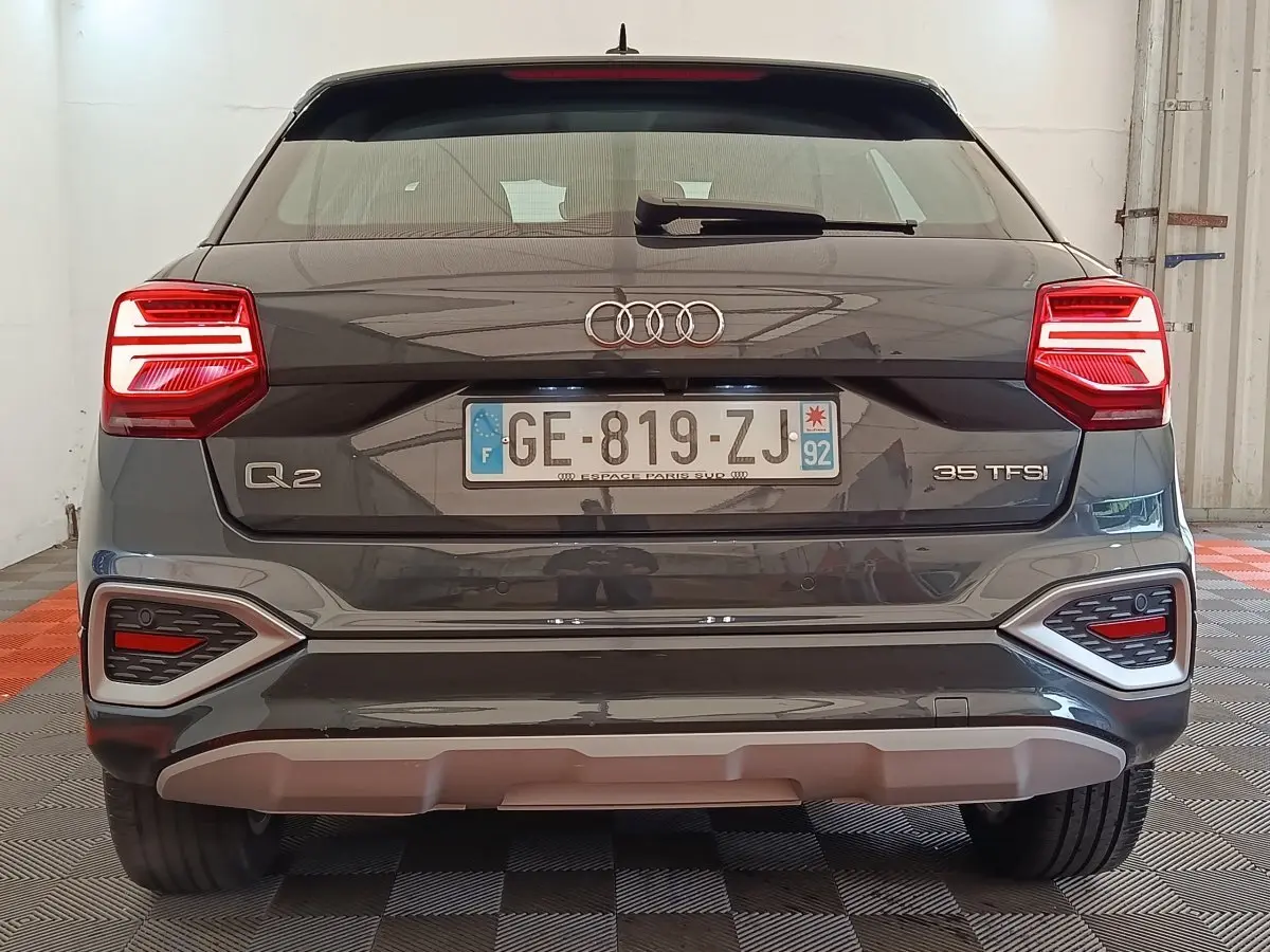Vue arrière d’un Audi Q2 gris foncé 35 TFSI 150 S Tronic avec feux LED et logo distinctif au centre.