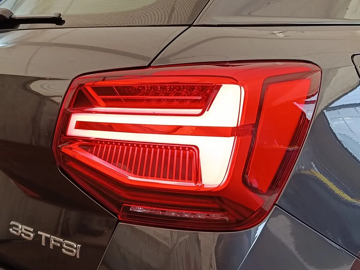 Gros plan sur le feu arrière droit rouge et blanc d’un Audi Q2 gris foncé 35 TFSI 150 S Tronic Business Line.
