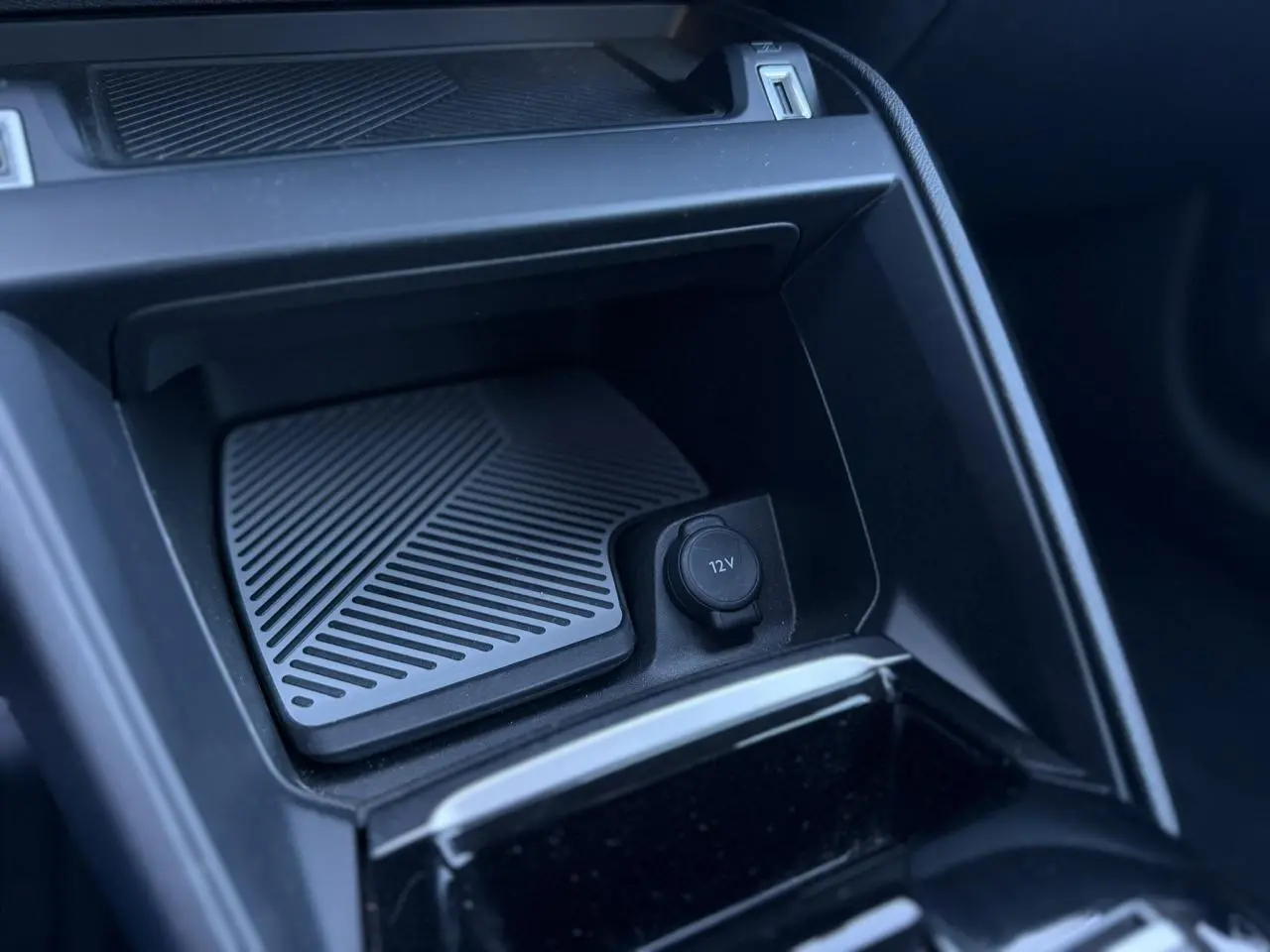 Détail de la console centrale intérieure de la Citroën C4 Hybrid 2025, prise en plongée montrant la prise 12V et un espace de rangement noir.