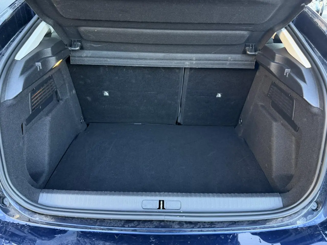 Coffre ouvert vu de l'arrière d'une Citroën C4 Hybrid 145 bleu Eclipse, espace de chargement vide et propre.