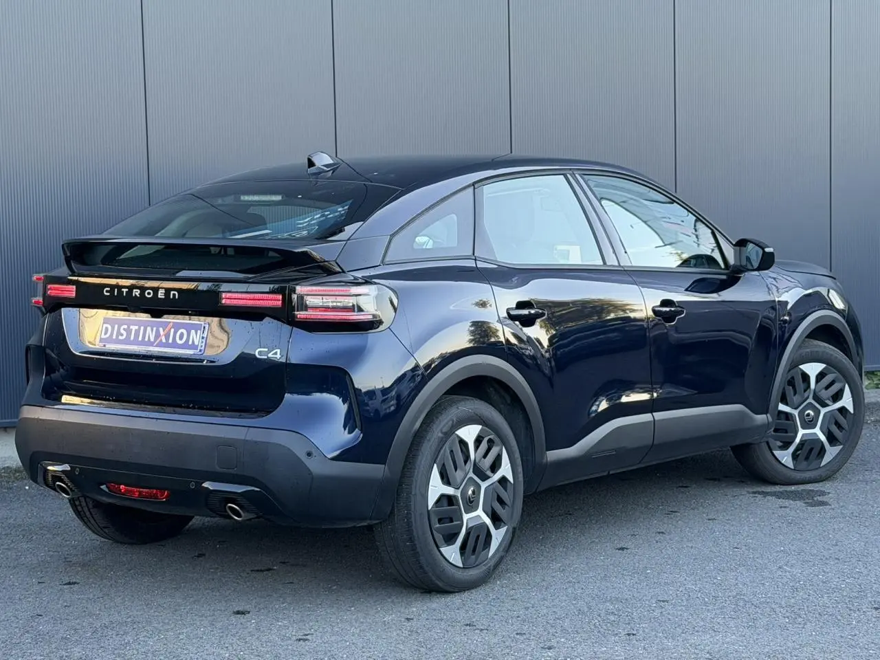 Vue 3/4 arrière droite d'une Citroën C4 Hybrid 145 bleu Eclipse avec feux arrière LED et jantes spécifiques.