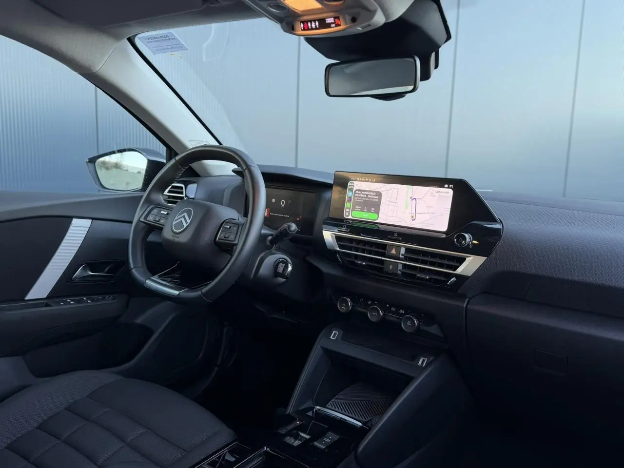 Intérieur avant de la Citroën C4 Hybrid 145, vue côté conducteur montrant le volant, tableau de bord et écran tactile central.