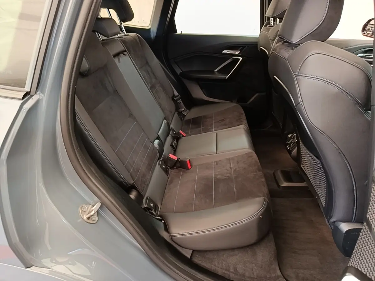 Vue intérieure arrière gauche montrant la banquette 3 places en cuir et alcantara du BMW X1 xDrive25e gris foncé 2023.
