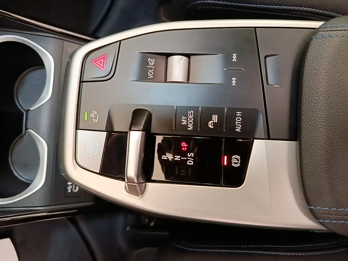 Vue rapprochée de la console centrale du BMW X1 xDrive25e M Sport 2023, avec levier de vitesses et commandes en alu noir et argent.