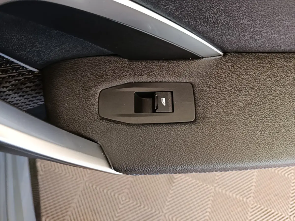 Détail du bouton de commande de vitre sur la garniture intérieure côté conducteur d’un BMW X1 gris foncé 2023.