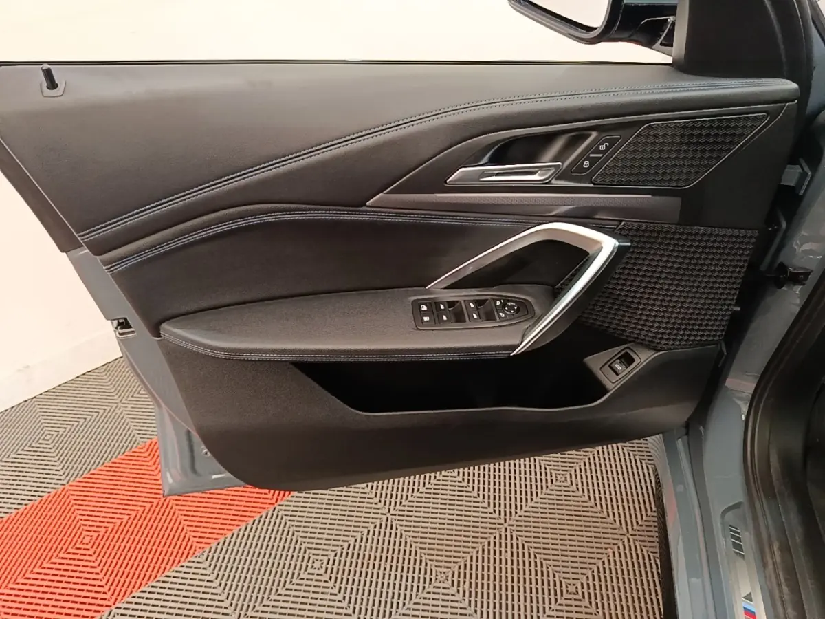 Vue rapprochée de la porte avant gauche gris foncé du BMW X1 xDrive25e M Sport avec garniture noire et insert alu.