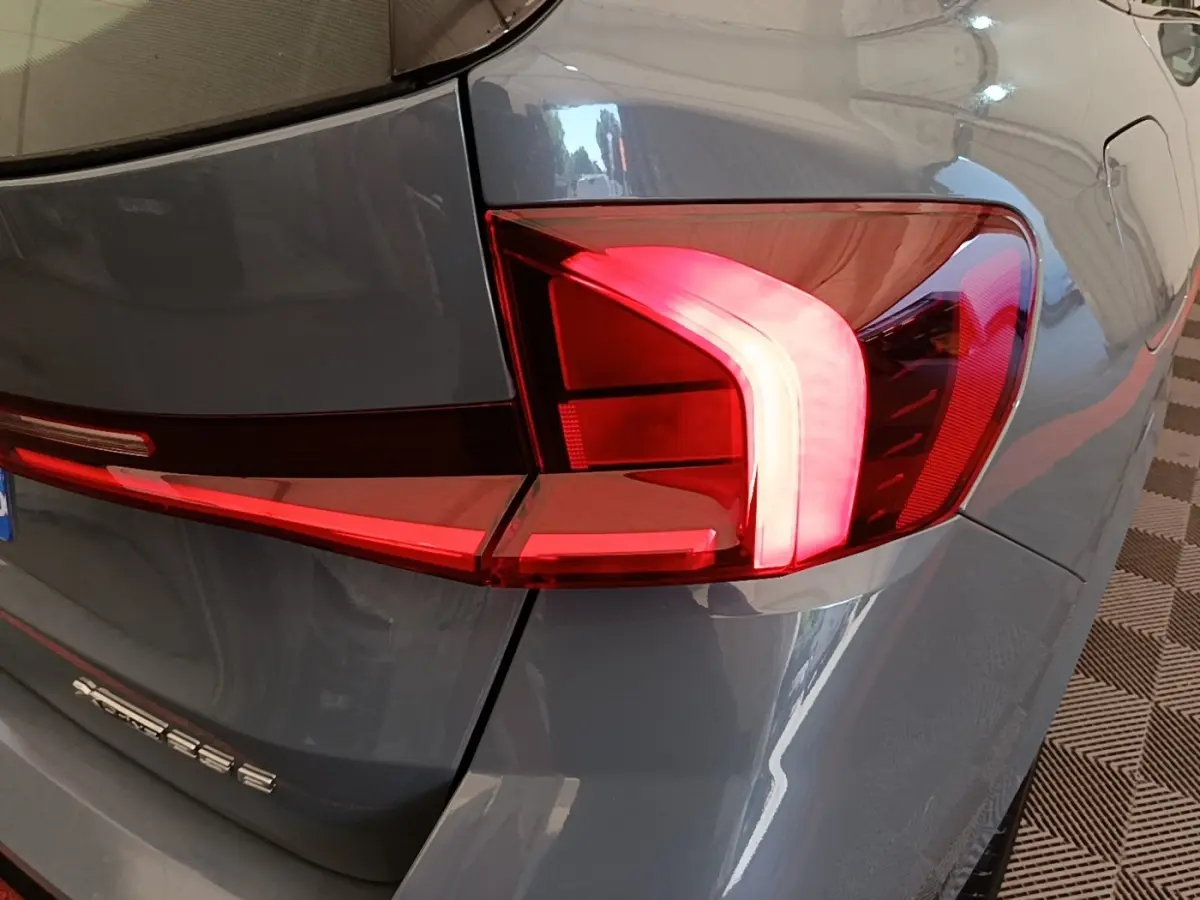 Gros plan sur le feu arrière droit rouge et blanc d’un BMW X1 xDrive25e M Sport gris foncé 2023.