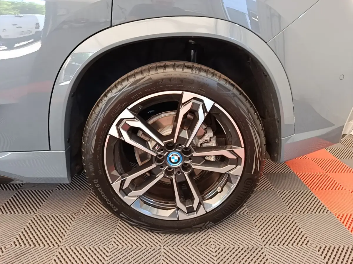 Gros plan sur la roue arrière droite d’un BMW X1 gris foncé avec jante alliage M Sport au design moderne.