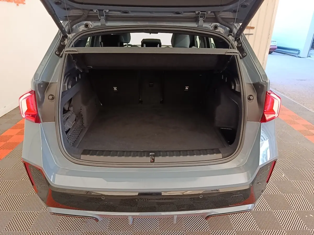 Vue arrière du coffre ouvert d’un BMW X1 xDrive25e M Sport gris foncé, montrant l’espace de chargement vide.