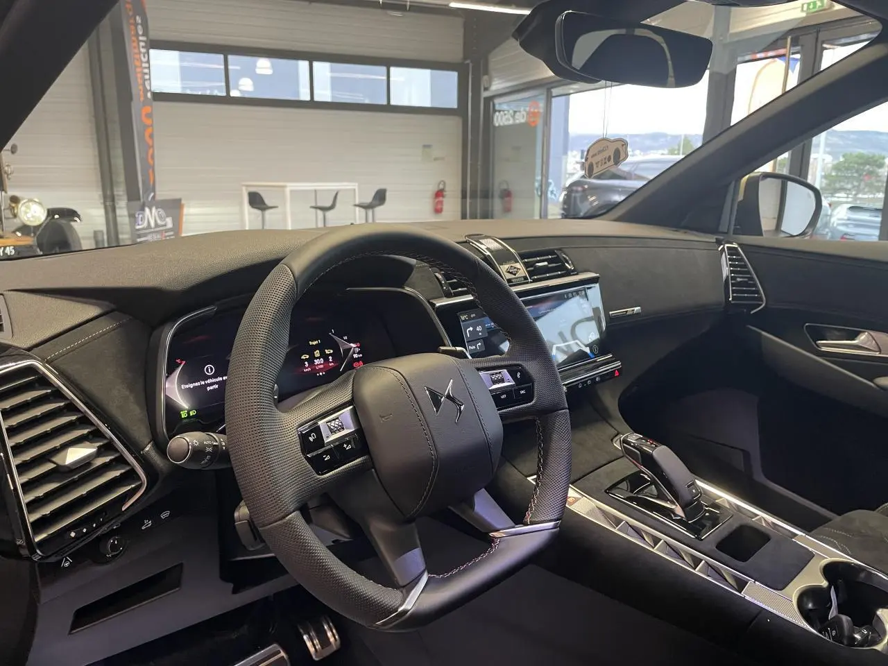 Vue intérieure côté conducteur du DS7 Crossback 2026 avec volant cuir perforé et tableau de bord Alcantara noir profond.