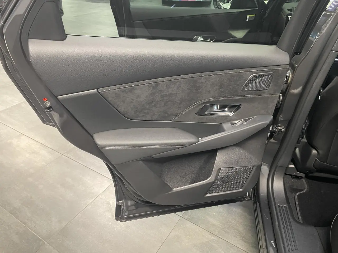 Porte arrière côté gauche ouverte d’un DS7 Crossback gris titanium, montrant le panneau intérieur en Alcantara noir et surpiqûres.