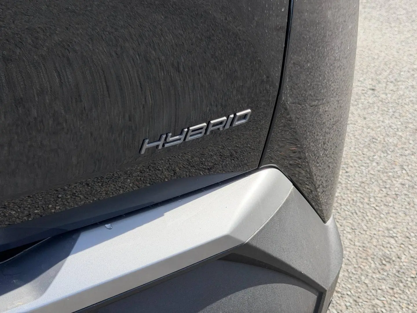 Gros plan sur l'arrière droit noir Perla Nera d'un Peugeot 3008 1.2 Hybrid avec logo Hybrid visible.