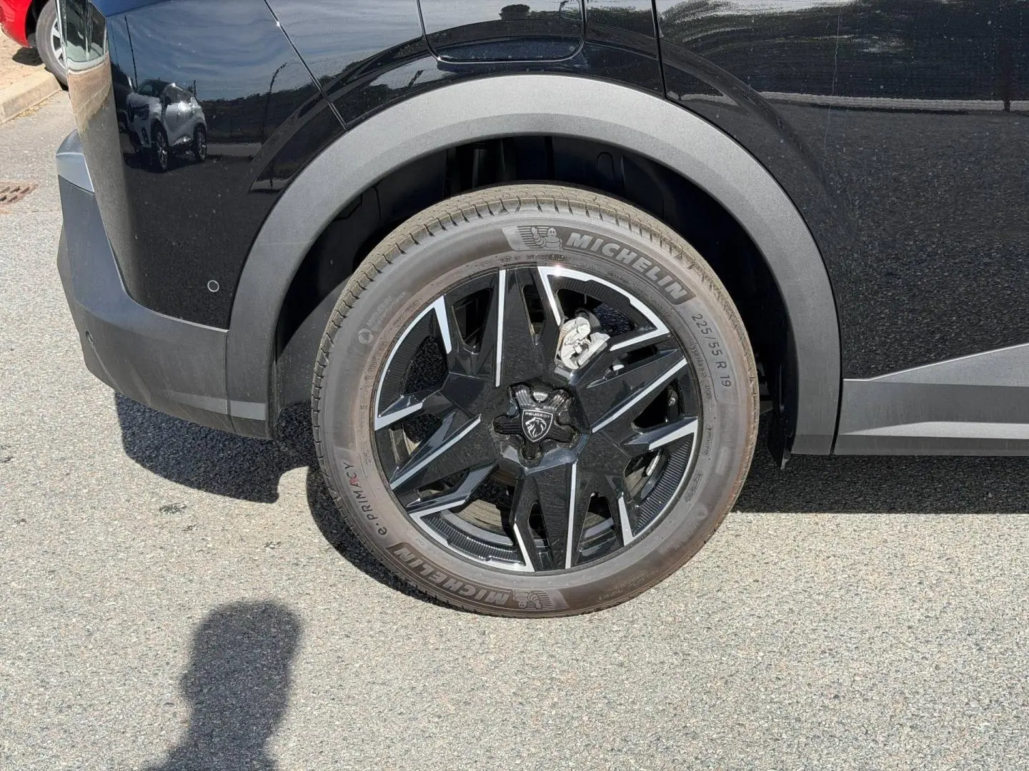 Gros plan sur la roue avant gauche d’un Peugeot 3008 noir Perla Nera avec jante alu noire et détails argentés.