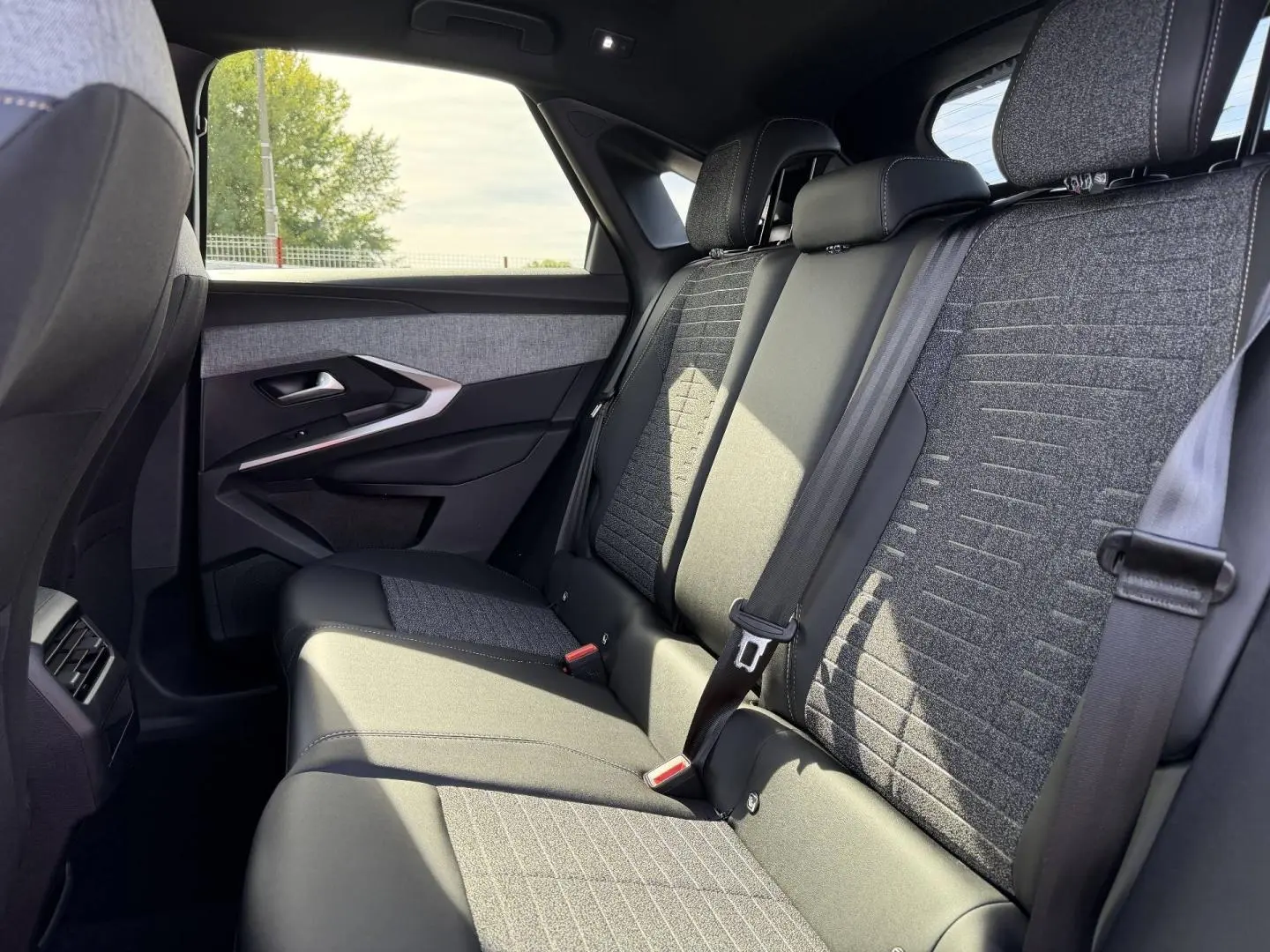 Vue latérale droite de la banquette arrière gris foncé et tissu CRISPY du Peugeot 3008 2026, avec ceintures de sécurité visibles.