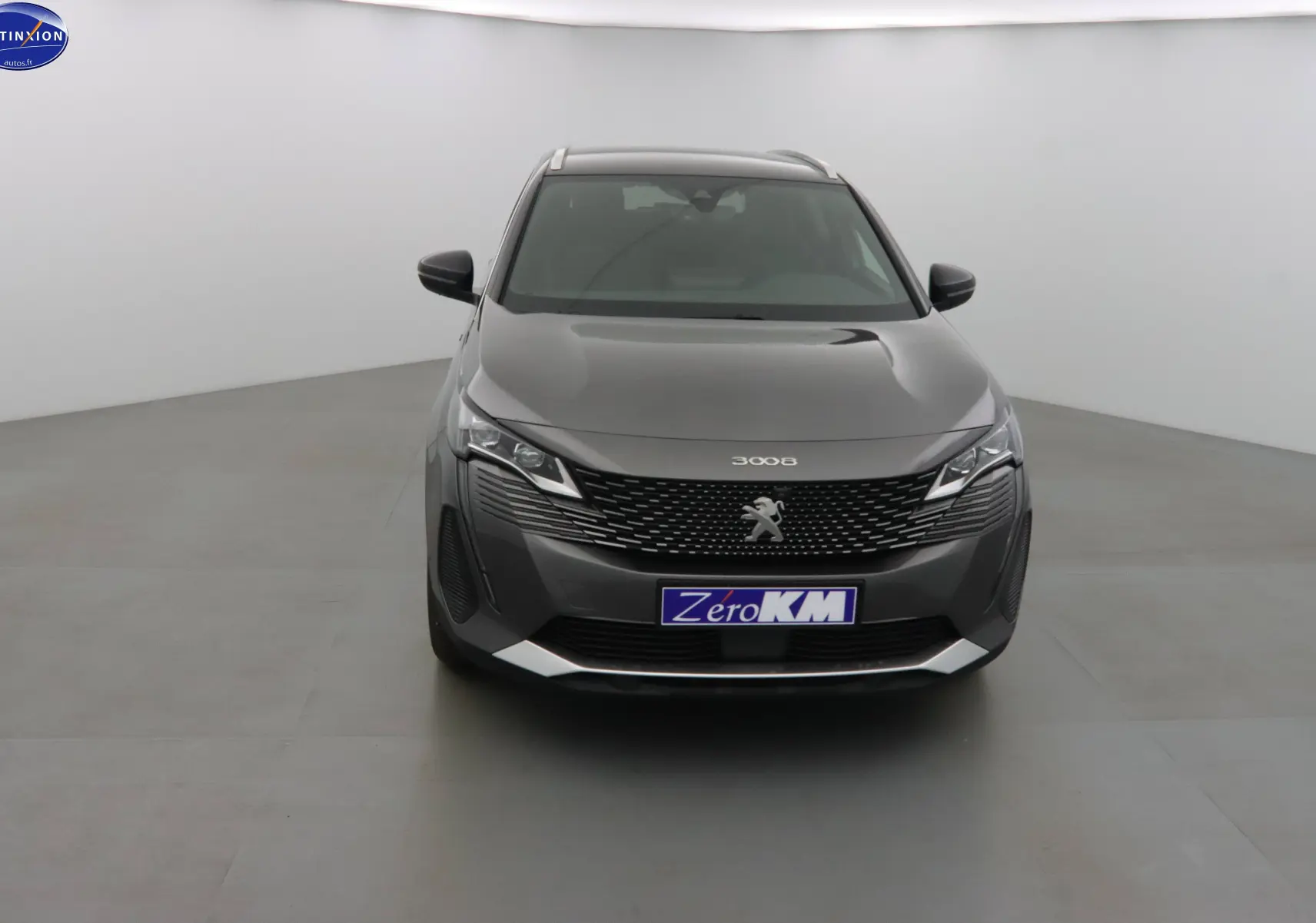 Vue frontale d'un Peugeot 3008 gris platinium métal 2023 avec calandre noire et logo lion central.