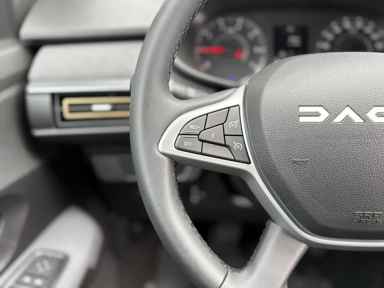 Gros plan sur le volant noir du Dacia Jogger 2025 avec commandes de régulateur de vitesse et logo central visible.