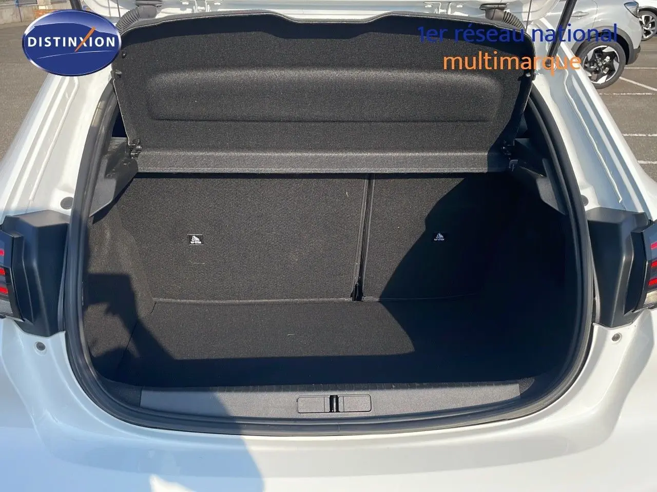 Coffre ouvert vu de l'arrière d'une Peugeot 208 blanc banquise, montrant l'espace de chargement vide et propre.