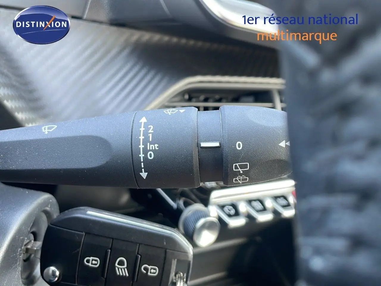 Gros plan sur la commande des essuie-glaces dans l'habitacle de la Peugeot 208 blanche, avec tableau de bord en arrière-plan.