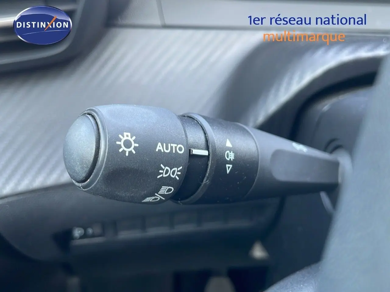 Gros plan sur la commande des phares du Peugeot 208 2024, intérieur noir avec réglage automatique des feux.