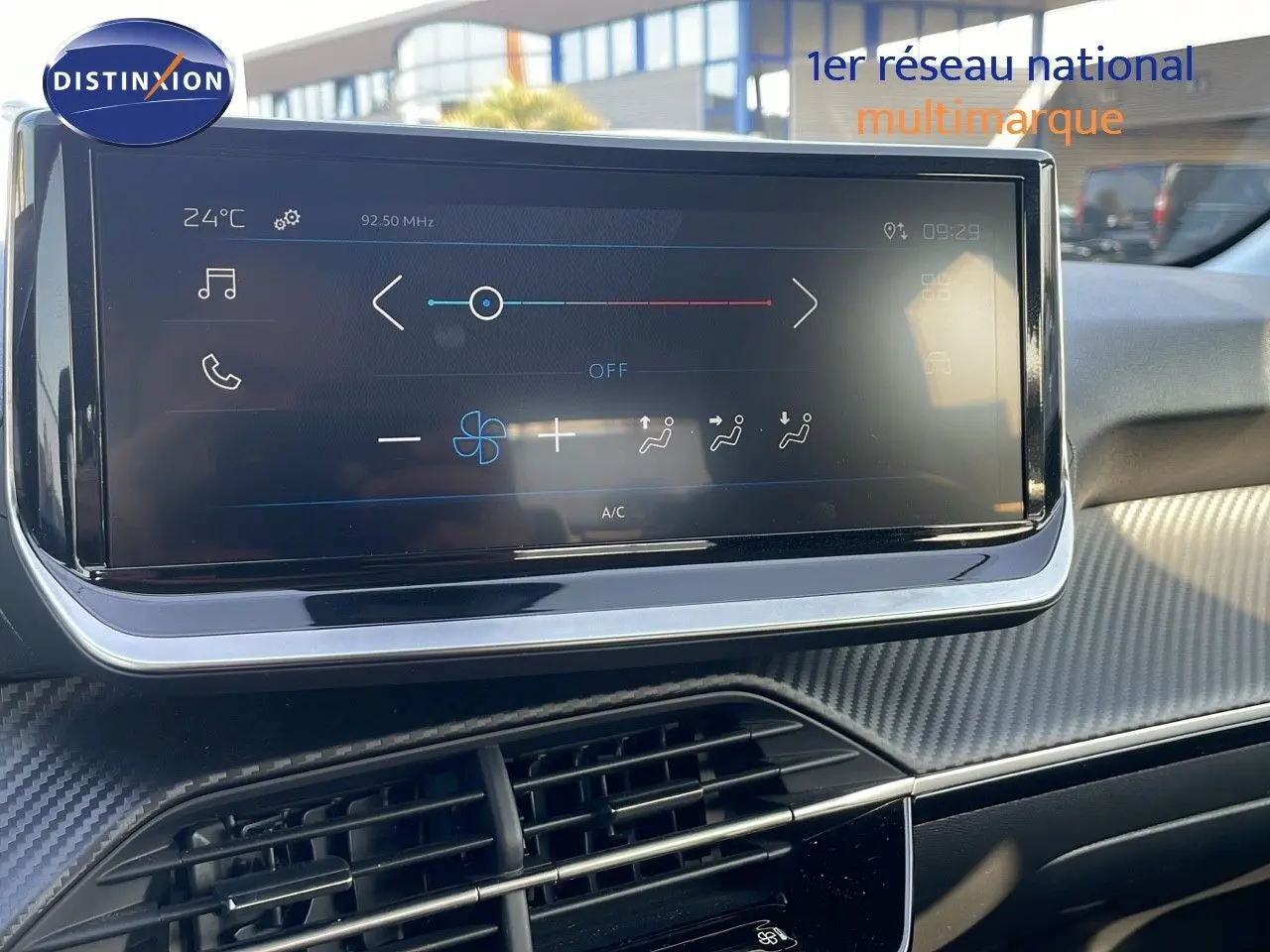 Écran tactile central du tableau de bord de la Peugeot 208 2024, avec commandes climatisation et finition carbone.