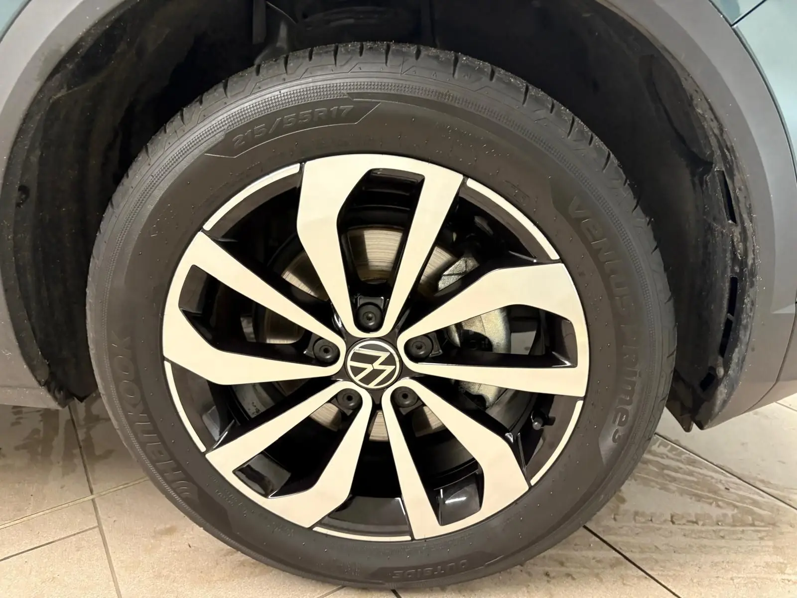 Gros plan sur la jante alliage bicolore du Volkswagen T-Roc 1.5 TSI bleu pétrole, roue avant droite visible.