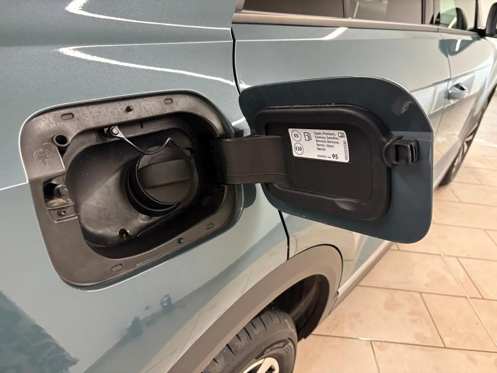 Vue de côté gauche sur le réservoir ouvert du Volkswagen T-Roc bleu pétrole, mettant en valeur la trappe à essence.