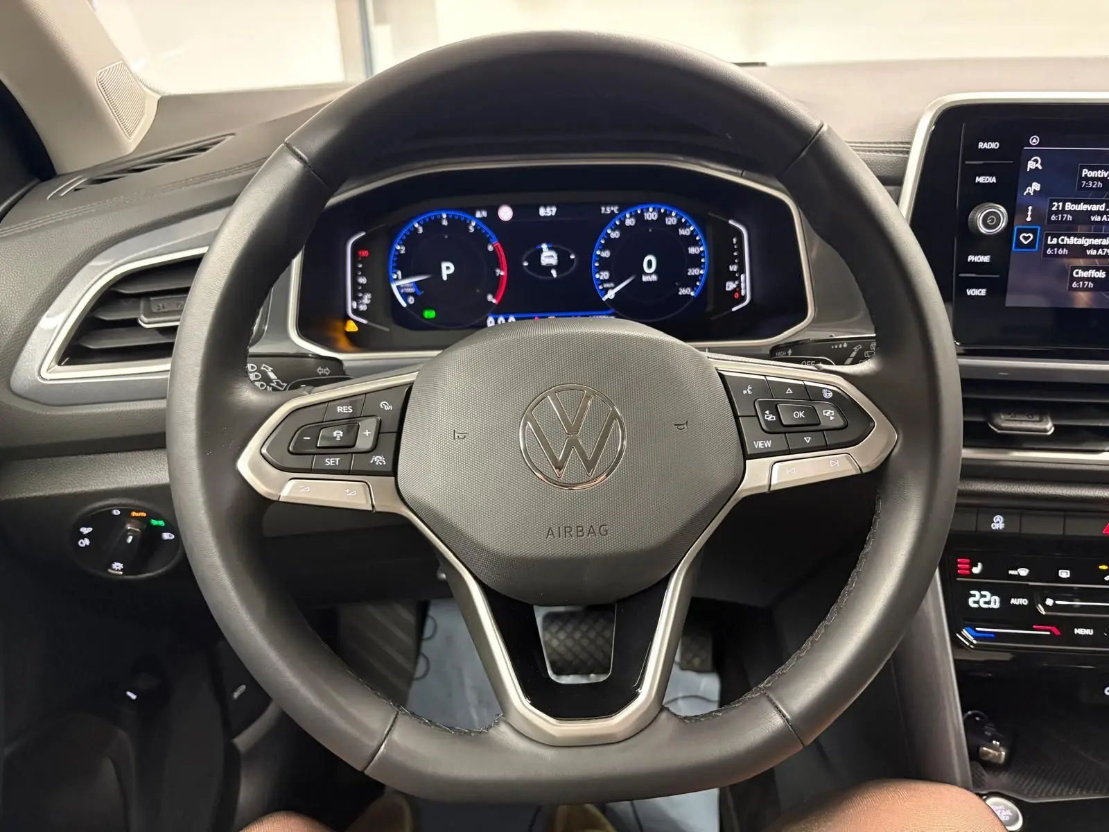 Vue centrée sur le volant multifonction noir du Volkswagen T-Roc 2025, avec tableau de bord digital et commandes visibles.