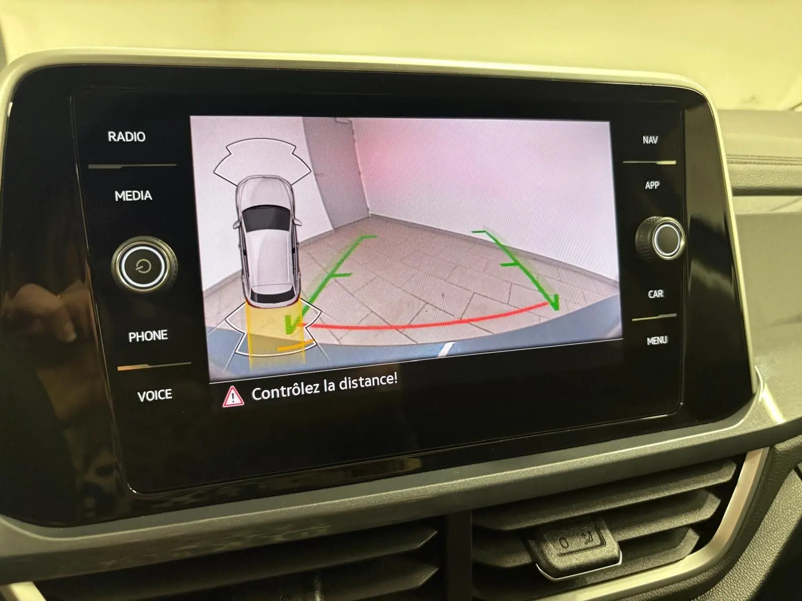 Écran central affichant la caméra de recul du Volkswagen T-Roc bleu pétrole avec guidage de trajectoire en intérieur.