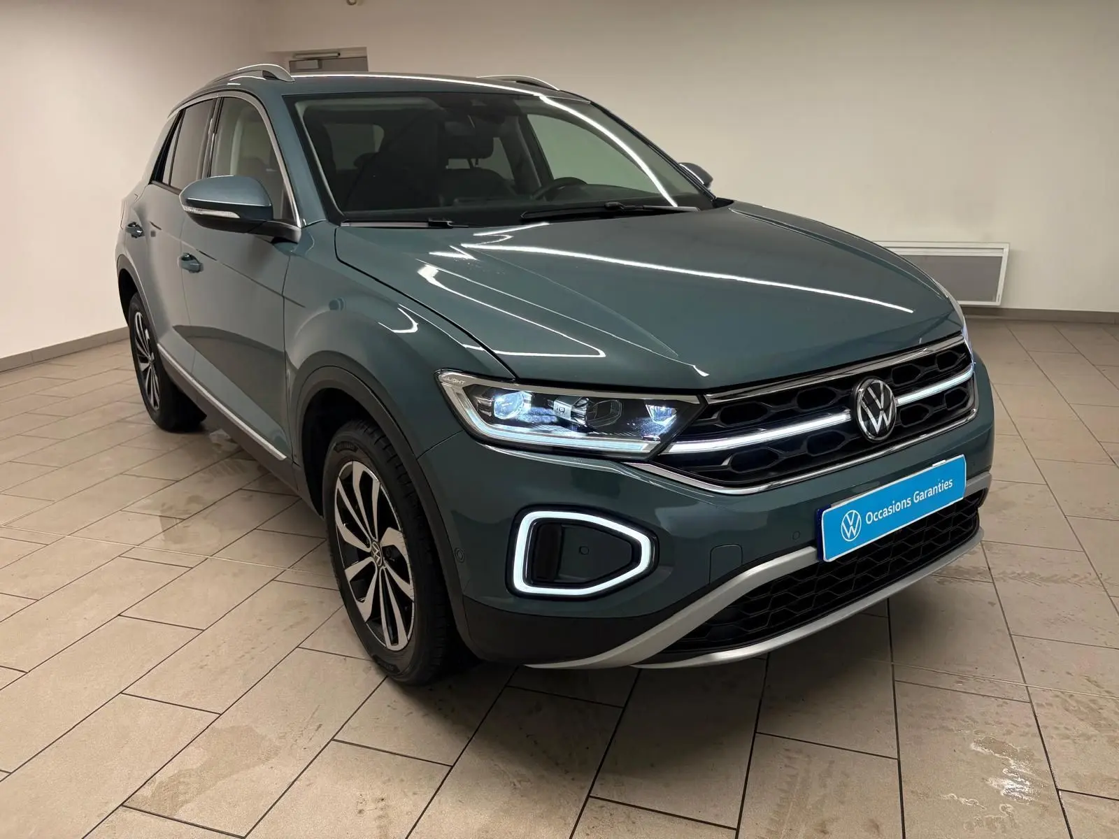 Volkswagen T-Roc 1.5 TSI bleu pétrole en 3/4 avant droit, avec feux LED et jantes alliage distinctives.