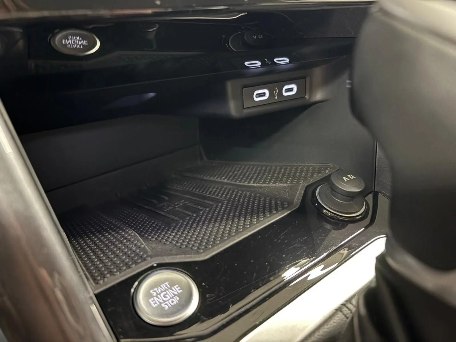Gros plan sur la console centrale du Volkswagen T-Roc bleu pétrole, montrant le bouton start/stop et les ports USB.