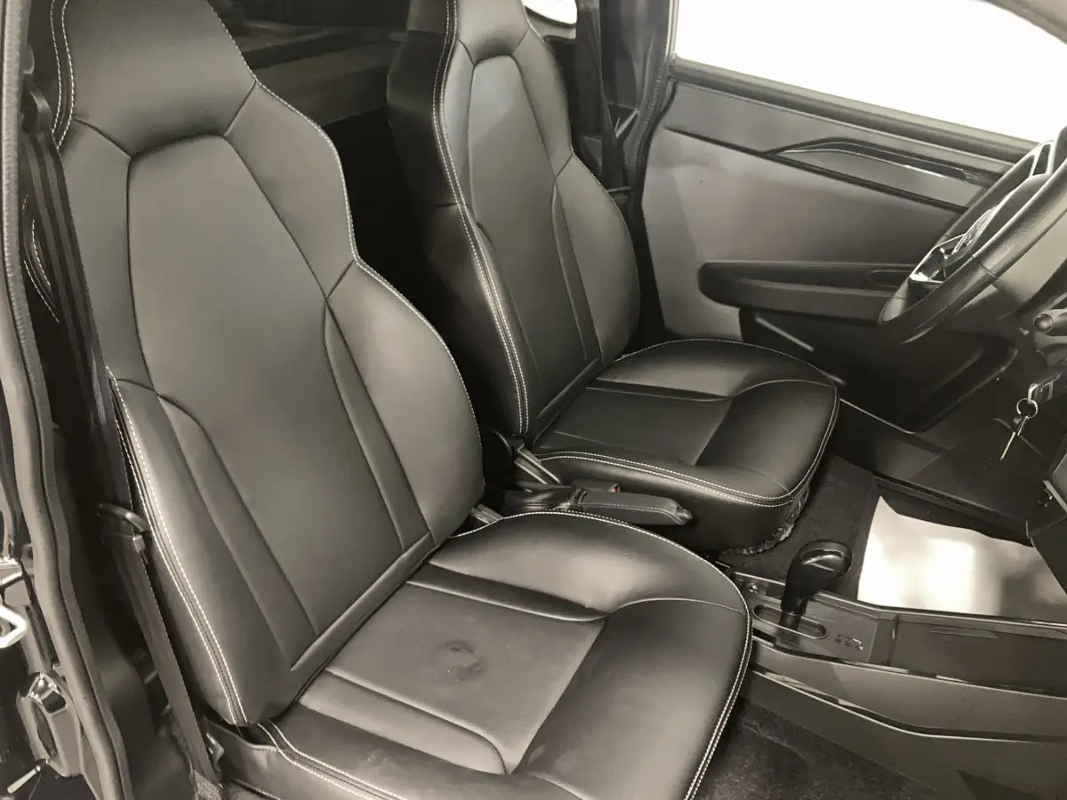 Vue intérieure côté conducteur du Ligier JS50 0.5 REVO D+ Select noir, sièges confort en cuir avec surpiqûres blanches.