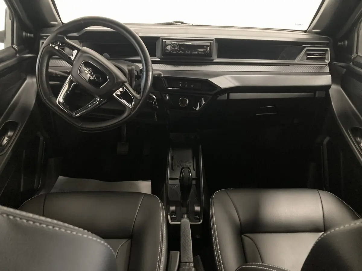 Vue intérieure frontale du tableau de bord noir de la Ligier JS50 0.5 REVO D+ avec volant et autoradio Pioneer intégré.