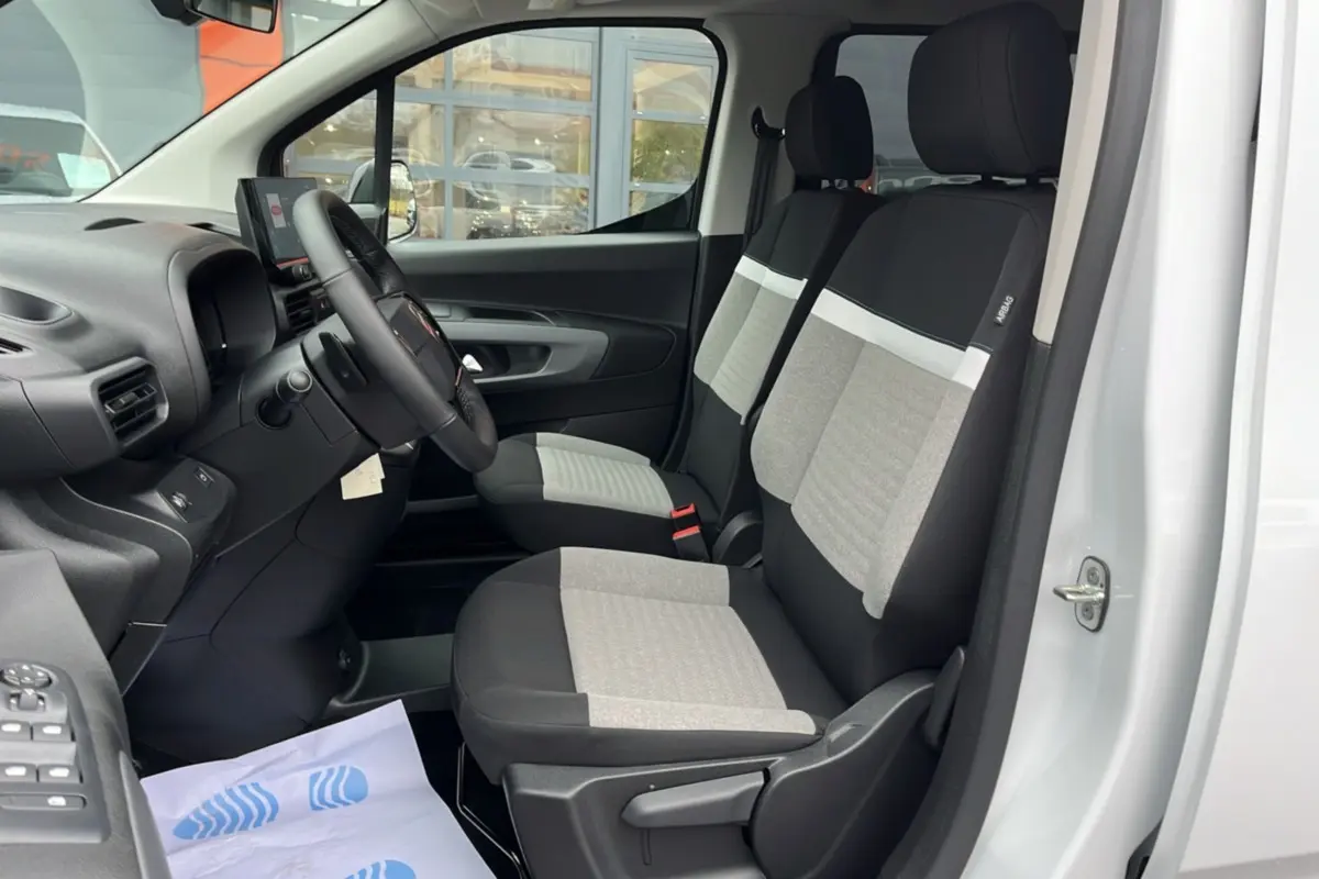 Vue intérieure côté conducteur du Citroën Berlingo blanc, montrant les sièges tissu bicolores et le volant multifonctions.