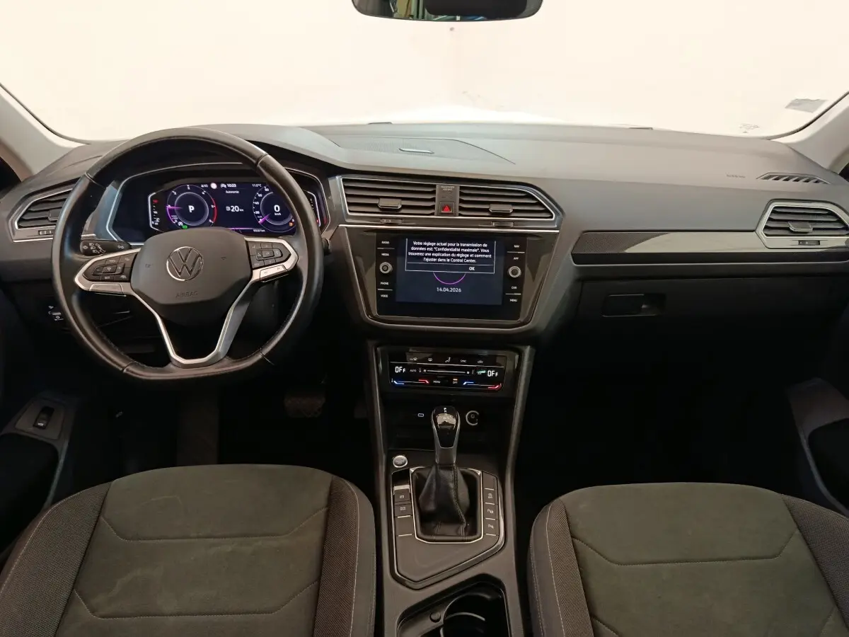Vue intérieure avant du Volkswagen Tiguan 2.0 TDI 2022, tableau de bord noir avec écran tactile et volant cuir multifonctions.