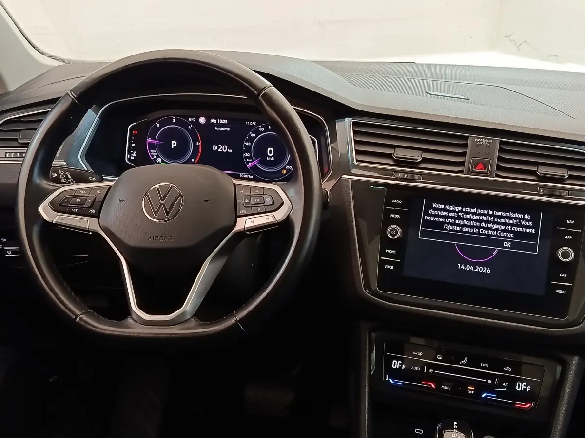 Vue intérieure centrée sur le volant cuir noir et l’écran tactile du tableau de bord du Volkswagen Tiguan 2022.