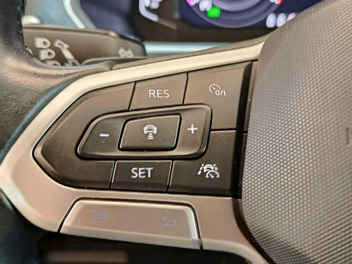 Gros plan sur les commandes du régulateur de vitesse au volant cuir du Volkswagen Tiguan noir 2022.