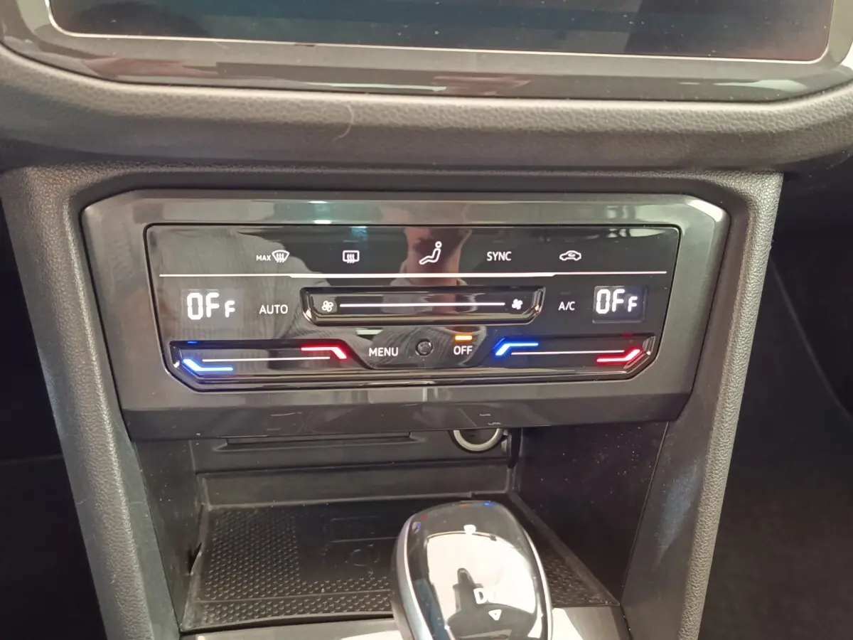Gros plan sur la console centrale du Volkswagen Tiguan 2022, avec commandes climatisation et levier de vitesse noir brillant.