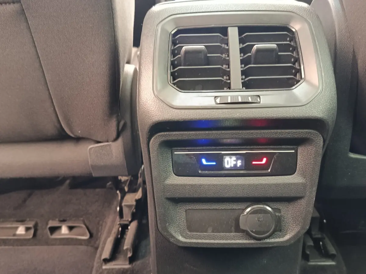 Vue rapprochée de la console arrière noire du Volkswagen Tiguan 2022, avec ventilation et commandes climatisation arrière éteintes.