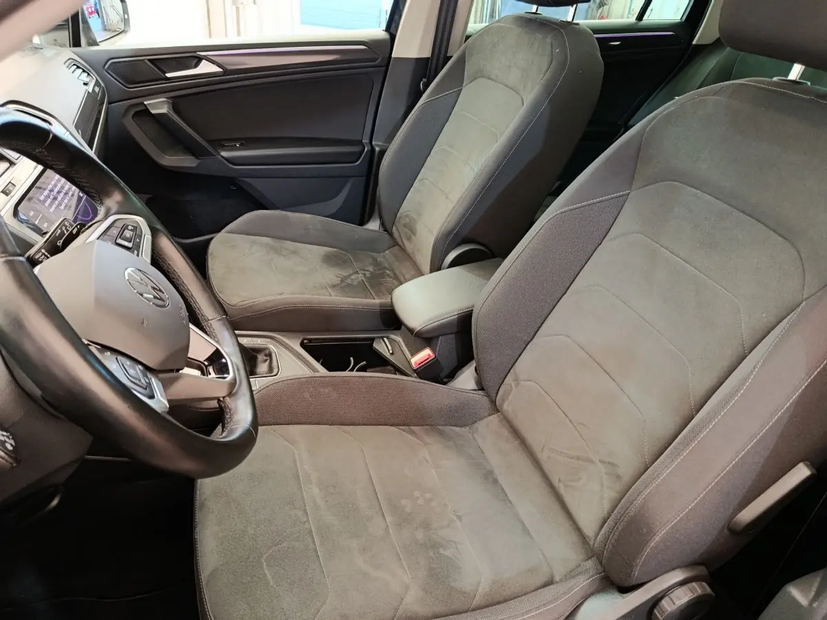 Vue intérieure rapprochée du Volkswagen Tiguan 2.0 TDI 150 DSG7 Elegance, sièges avant en tissu gris et volant cuir noir.