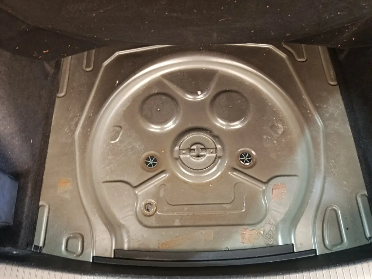 Coffre ouvert montrant le logement noir du pneu de secours du Volkswagen Tiguan 2.0 TDI 150 DSG7 Elegance.