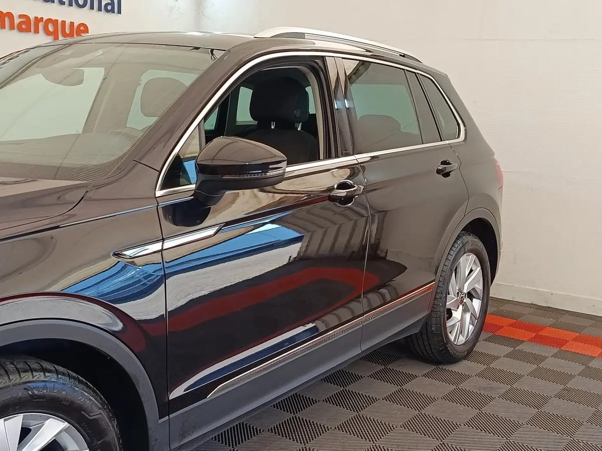 Vue côté gauche du Volkswagen Tiguan noir 2022, mettant en valeur les jantes alliage et les rétroviseurs avec clignotants intégrés.